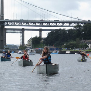 Group of kayakers paddling under old steel bridge