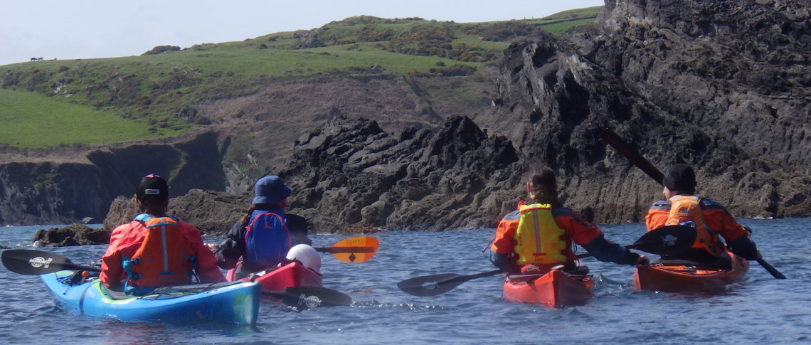 Group of kayakers along a rocky coast